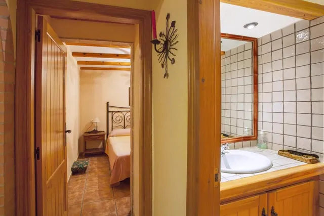 Aseo con mueble de madera y lavabo, junto al paso que comunica con uno de los dormitorios