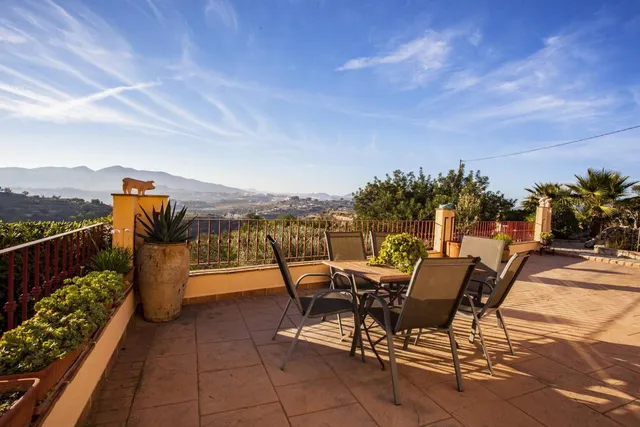 Terraza alta con mesa y sillas de jardín, macetones de barro y vistas abiertas al valle y a la sierra