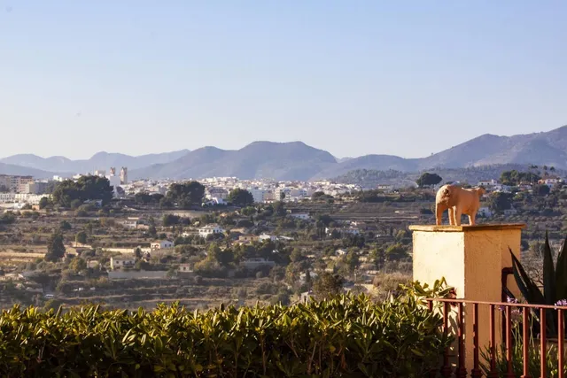 Vista del pueblo de Benissa desde la villa, con la torre de la iglesia destacando sobre los bancales y la sierra al fondo